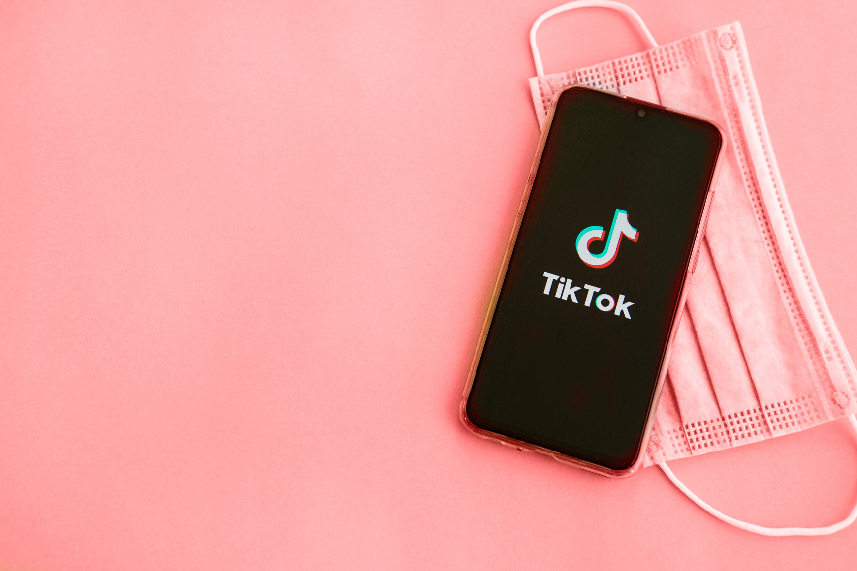 Tver, Russia - September 19, 2020: Tiktok App on the Smartphone Screen and Medical Protective Mask on a Green Background. TikTok Is a Popular Video Sharing Social Network Owned by ByteDance.