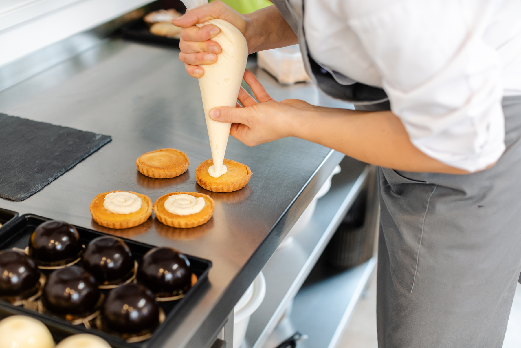 Pastry Chef Using Icing Bag to Put Creme on Cake